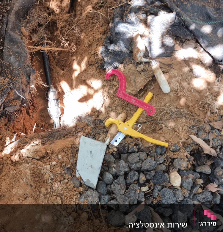 כלי עבודה וצינור חשוף בחפירה באדמה